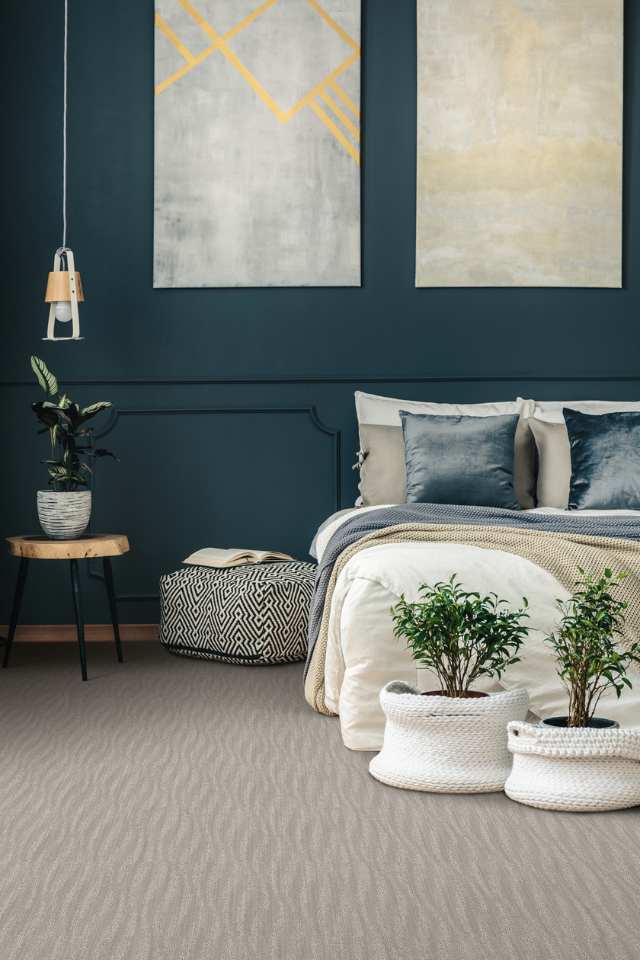 grey wavy patterned carpet in bedroom with navy blue accent wall and artwork 